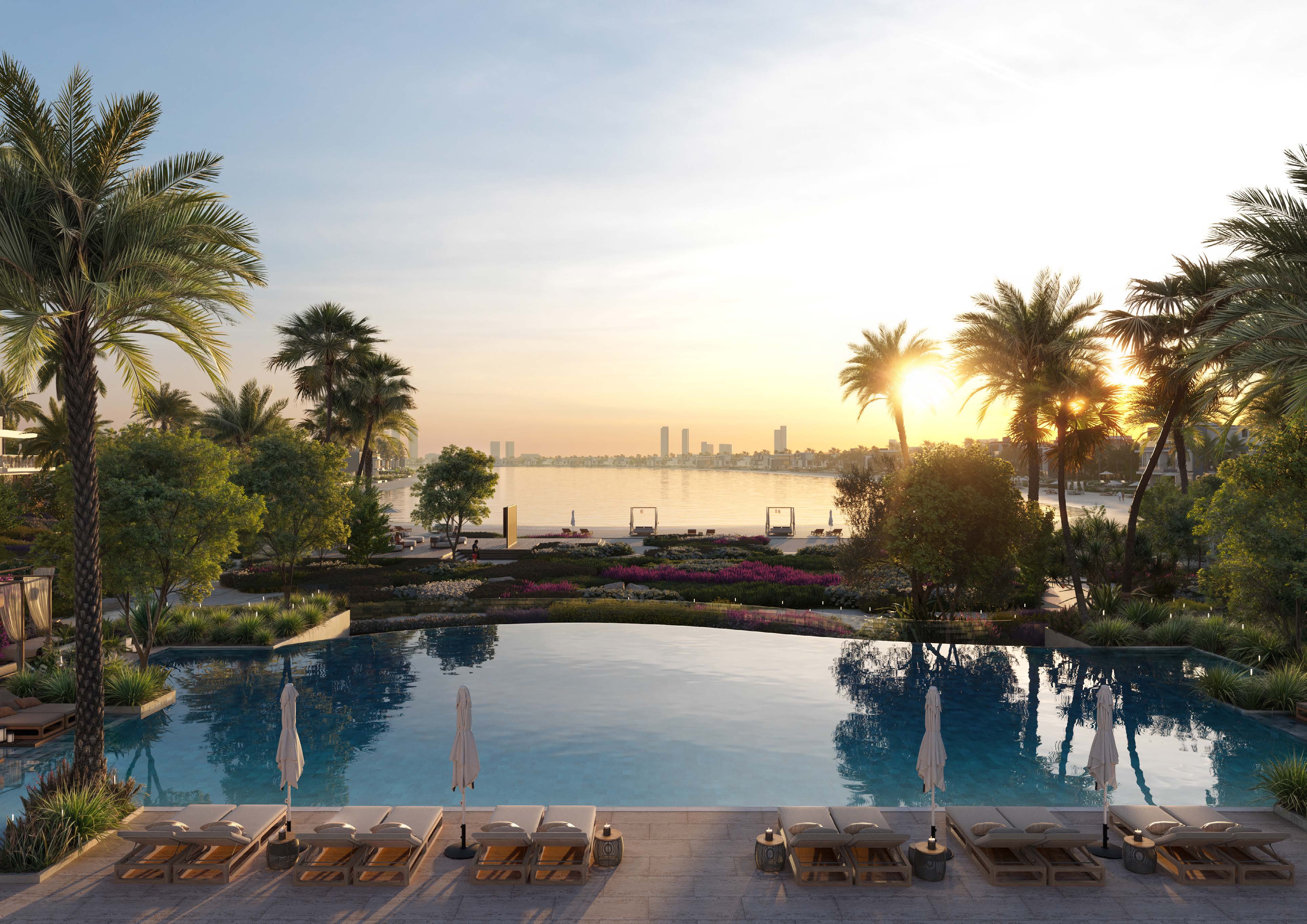 Infinity pool with sun loungers, gardens and the bay at sunset